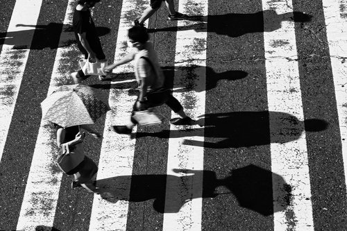 白黒の横断歩道を渡る人影、縞模様の道路上で交通する都市風景