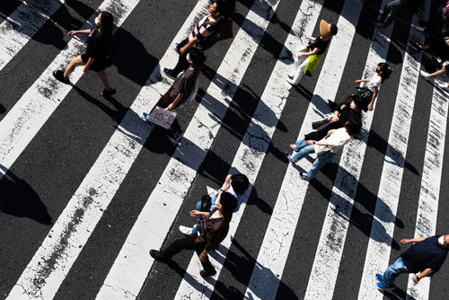 昼間の日差しが映る横断歩道の縞模様と複数の人影