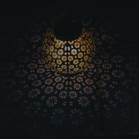 暗闇に浮かび上がる花柄ランタンの灯りと壁面の影の写真