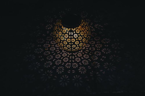 暗闇に浮かび上がる花柄ランタンの灯りと壁面の影