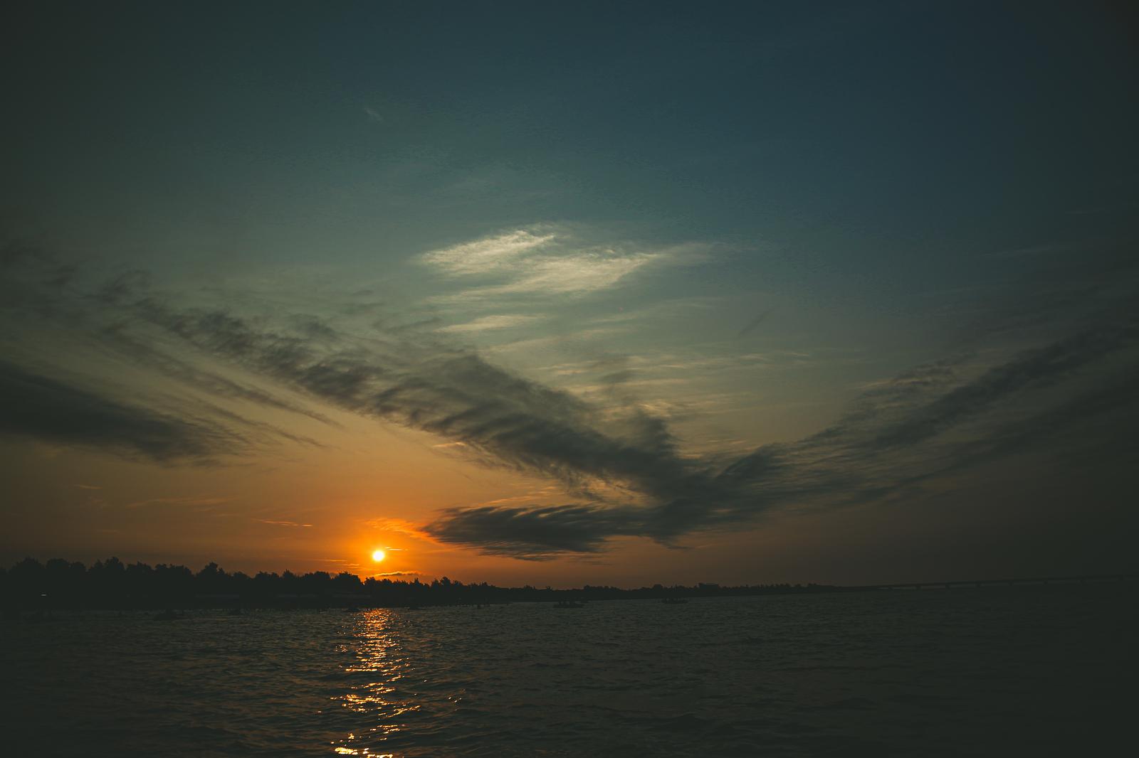 湖の水面に映る夕日と雲の風景