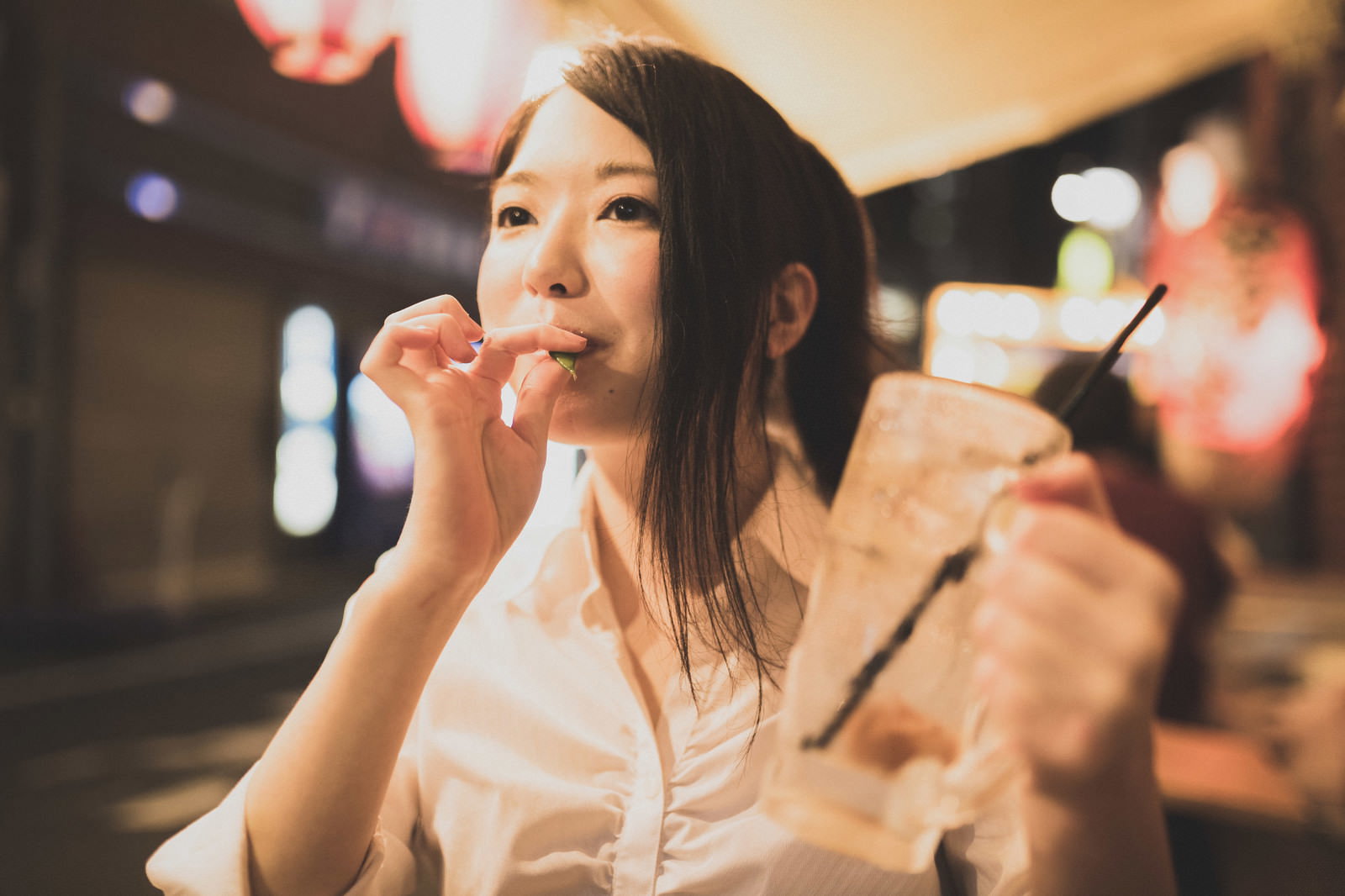 居酒屋でチューハイを持ちながら枝豆を食べる女性［モデル：シマヅ］