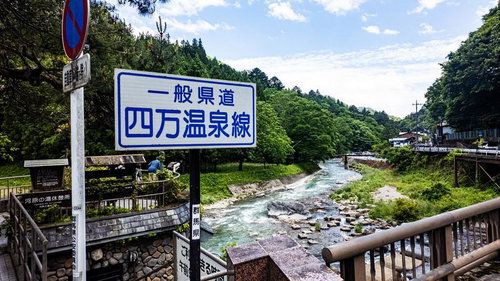 四万温泉線の標識と渓流