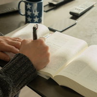 資格試験の勉強中、ペンを握りながら教科書を読むの写真