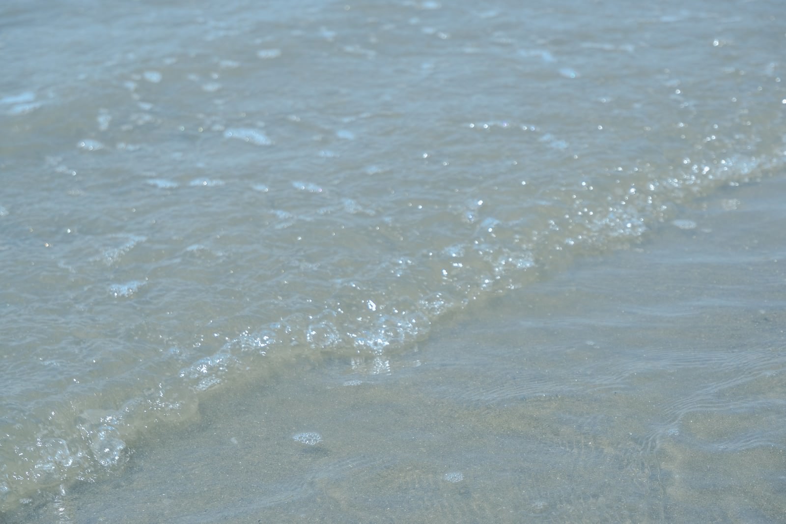 透明な海水が海岸に打ち寄せ白い泡を立てるさざ波
