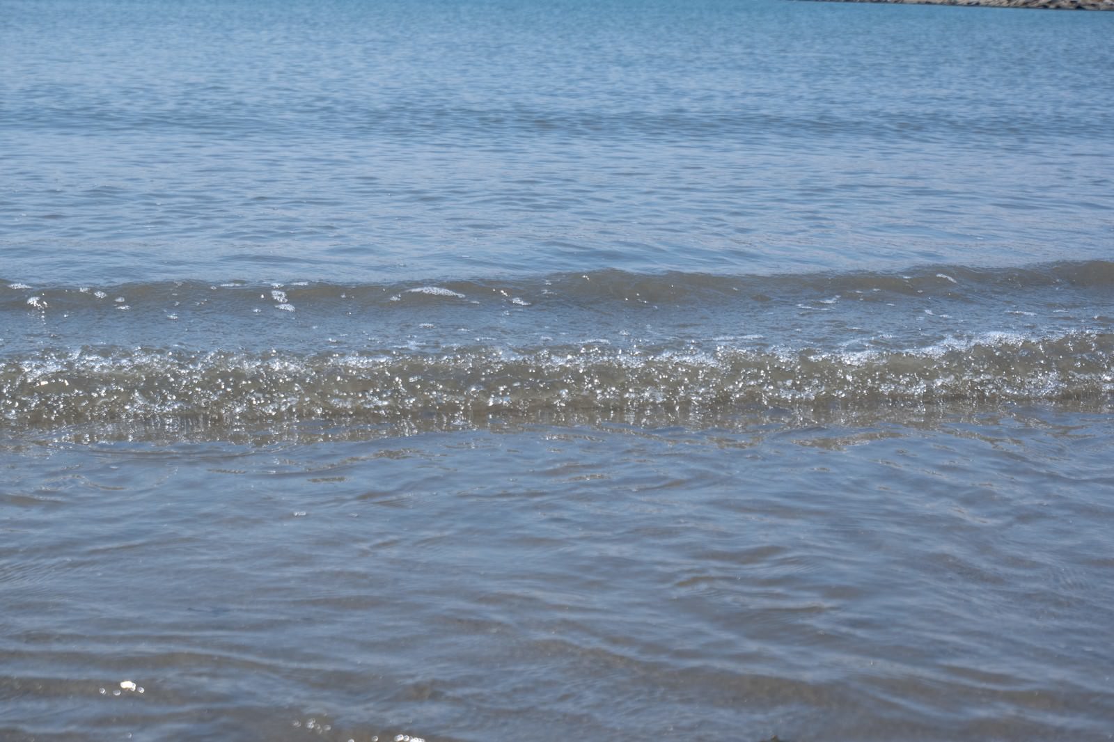 穏やかな海の波打ち際で小さな波が砂浜に打ち寄せている