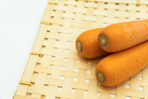 竹ざるの上に並ぶオレンジ色のにんじん2本