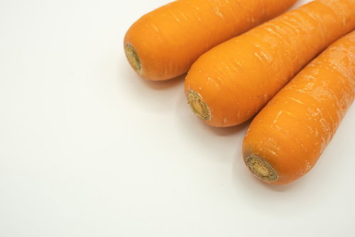 白い背景に並んだ新鮮なにんじん3つ。オレンジ色の野菜