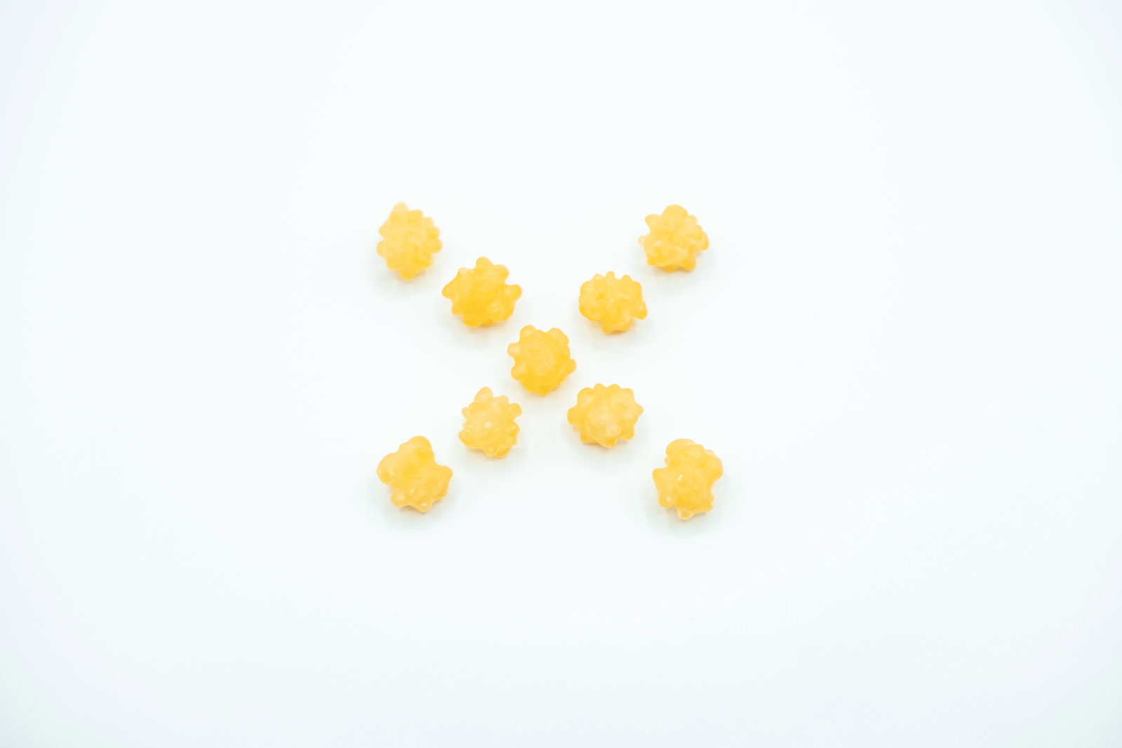 白い背景にオレンジ色のこんぺいとうでバツ印を作った写真