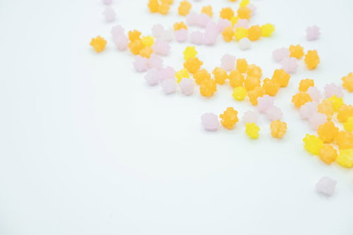 白い背景に散らばったオレンジ色の金平糖の