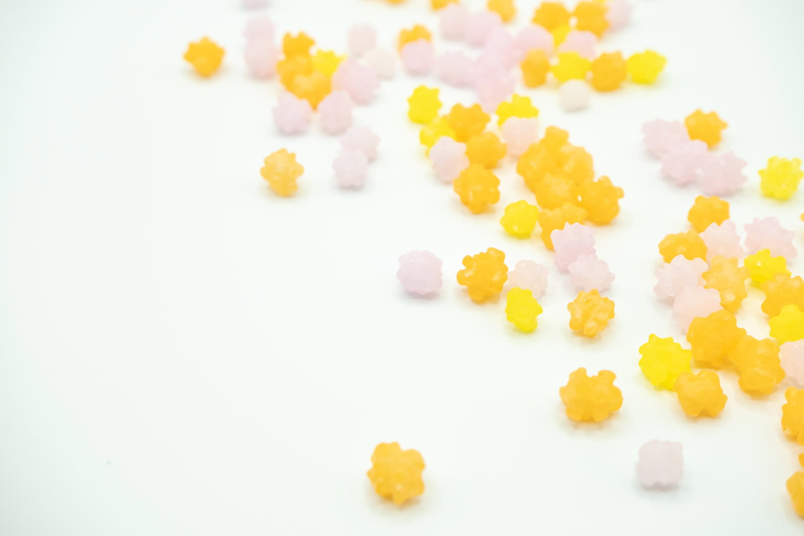 白い背景にオレンジや黄色、ピンクの小粒こんぺいとうが散らばっている