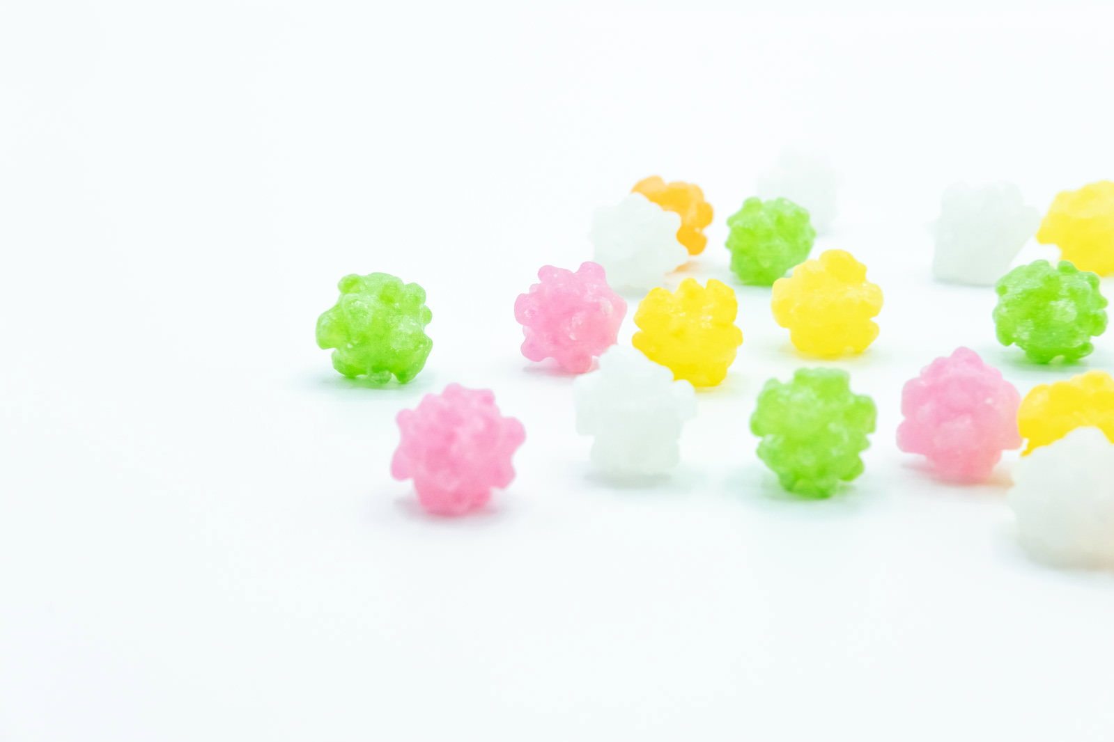 白い背景に散らばった緑、ピンク、黄色のこんぺいとう