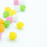 輝くカラフルな金平糖が白い背景に散らばるの写真