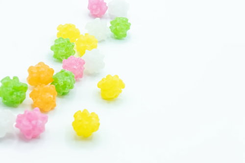 輝くカラフルな金平糖が白い背景に散らばる