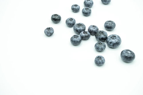 白い背景に散らばったブルーベリーの実と新鮮な生果