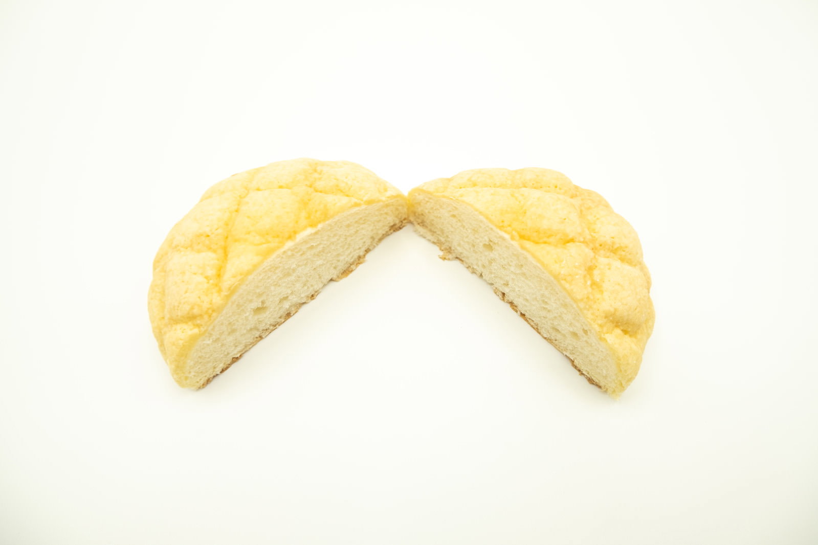 白い背景に置かれた半分にカットされたメロンパン