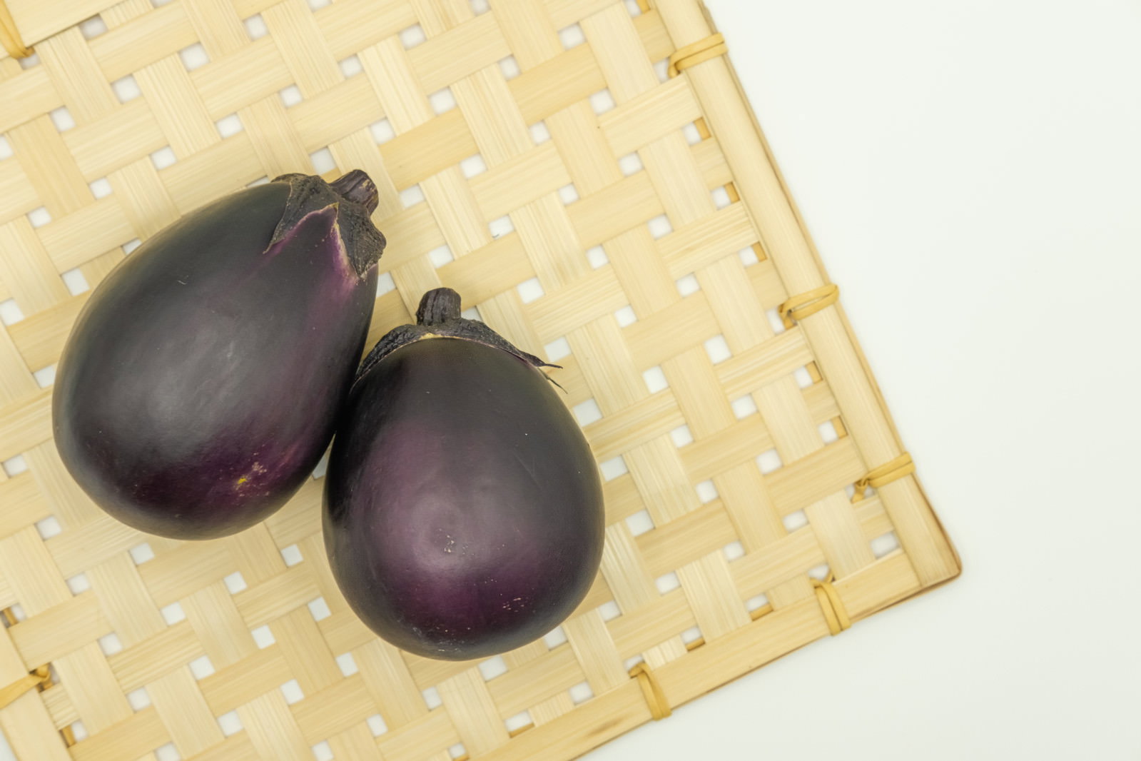 竹製のザルに載せられた2個の丸い茄子