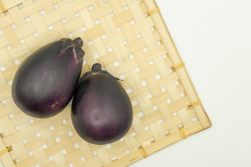 竹ざるの上に並ぶ丸茄子の写真
