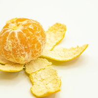 皮を剝いた早生みかんと散らばった黄色い皮の写真