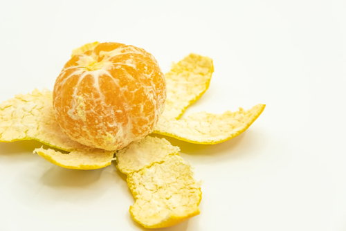 皮を剝いた早生みかんと散らばった黄色い皮