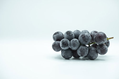 卓上に置いた種なし巨峰の房、新鮮な水滴付き