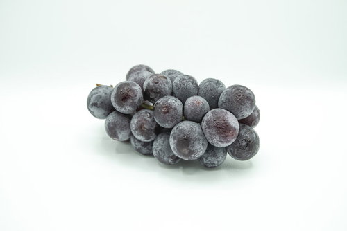 白い背景に置いた種なし巨峰の房、水滴付きの新鮮な葡萄