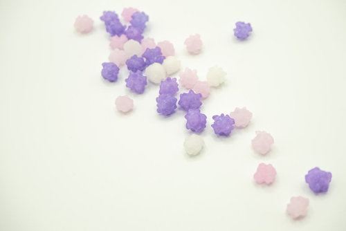 白い背景に散らばる藤色系のこんぺいとう、金平糖の和菓子
