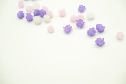 藤色系の金平糖が白い背景に散らばる様子