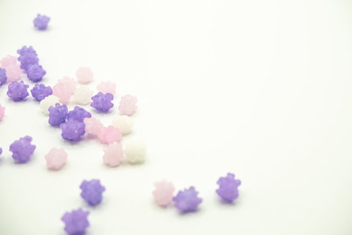 白い背景に散らばった藤色系の金平糖