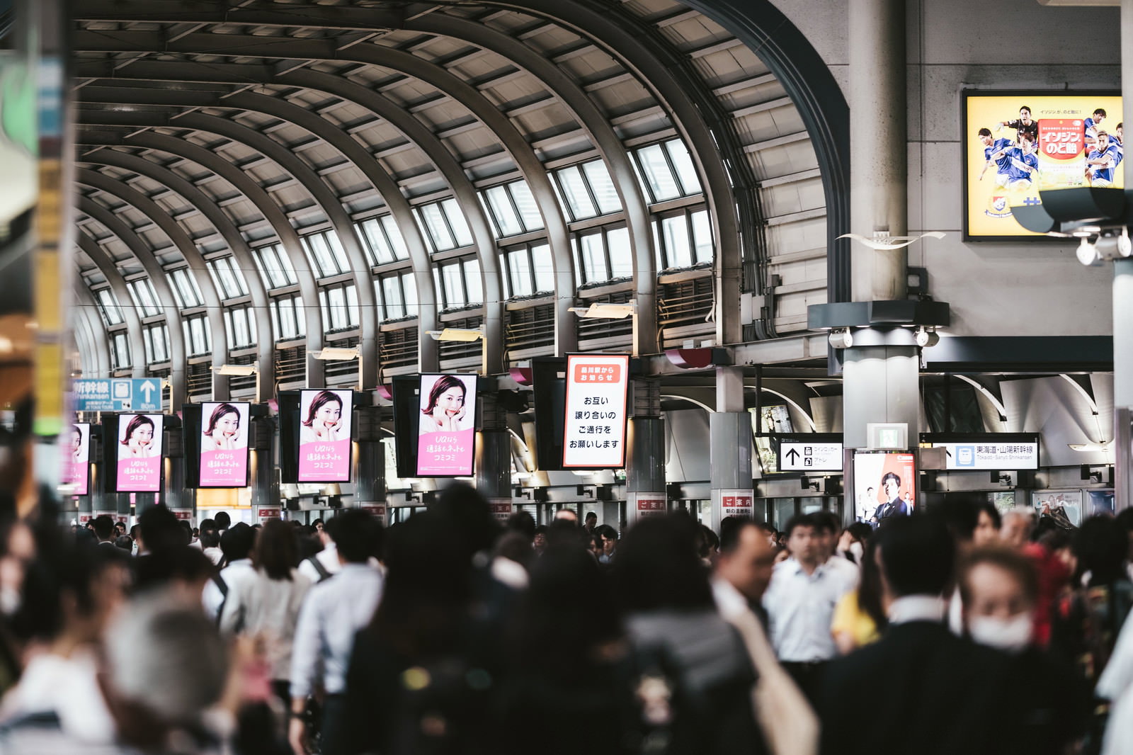 アーチ型の天井を持つ品川駅の自由通路で多くの人々が行き交う混雑した様子