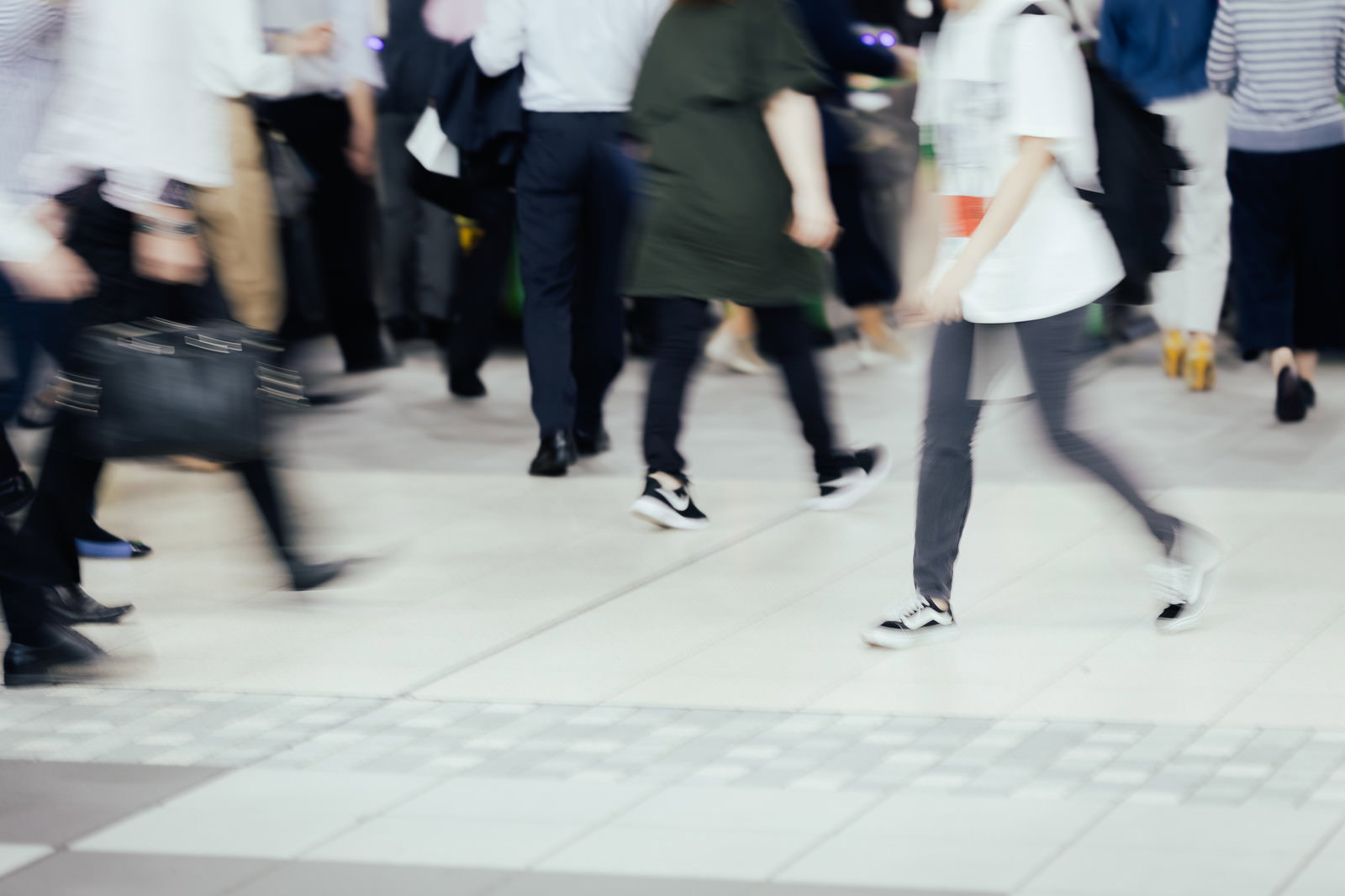 改札前で足早に歩く通勤ラッシュの人々をブレ表現で撮影