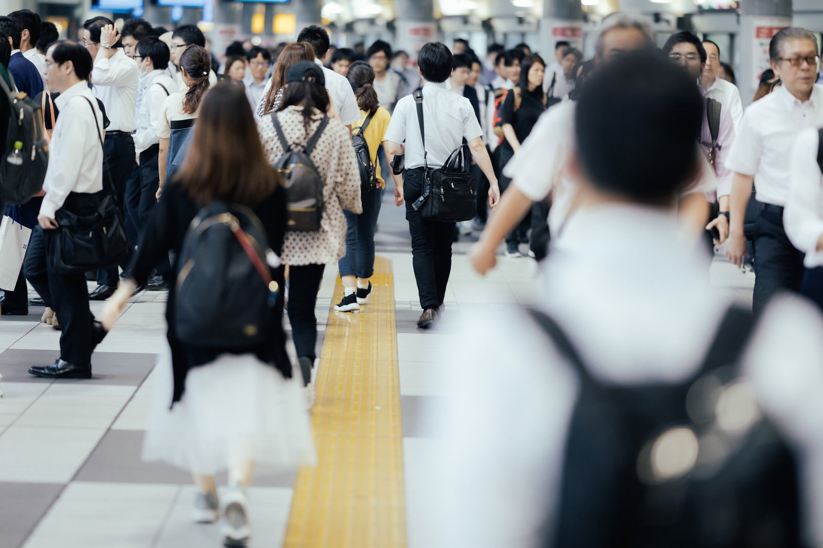 品川駅前で改札周辺を行き交う多くの会社員たちの様子