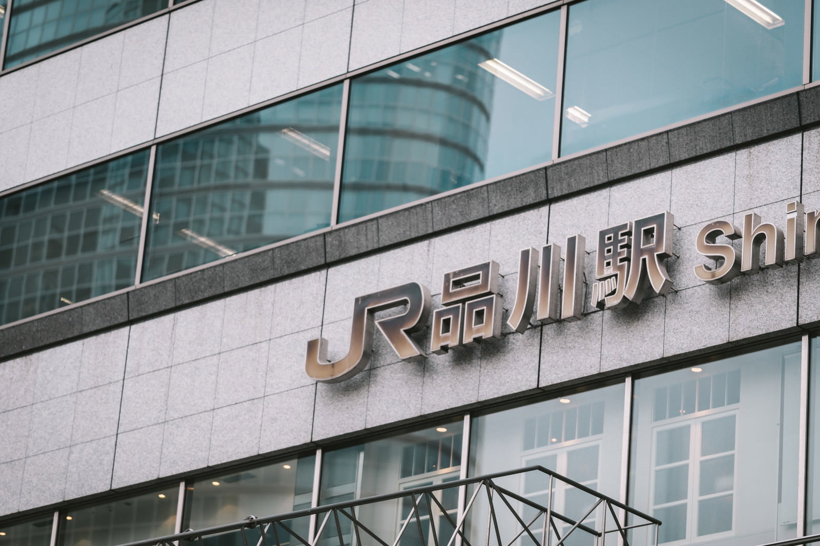 JR品川駅港南口の現代的なガラス張り建物と駅名看板