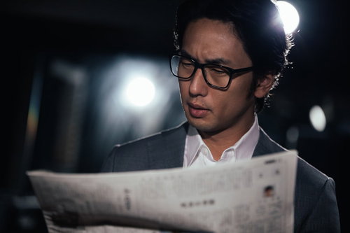 事件を紙面で知る刑事の男性が新聞を読む姿