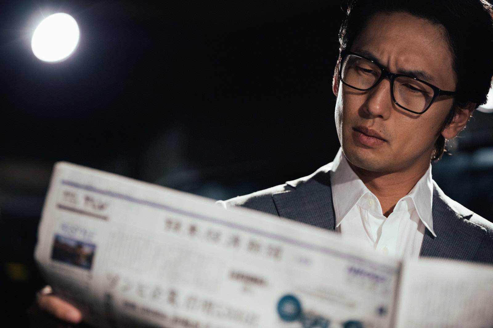 眼鏡をかけた男性が真剣な表情で経済新聞を読んでいる［モデル：大川竜弥］