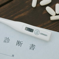 処方してもらった錠剤と診断書、体温計で示す高熱と医療対応の写真
