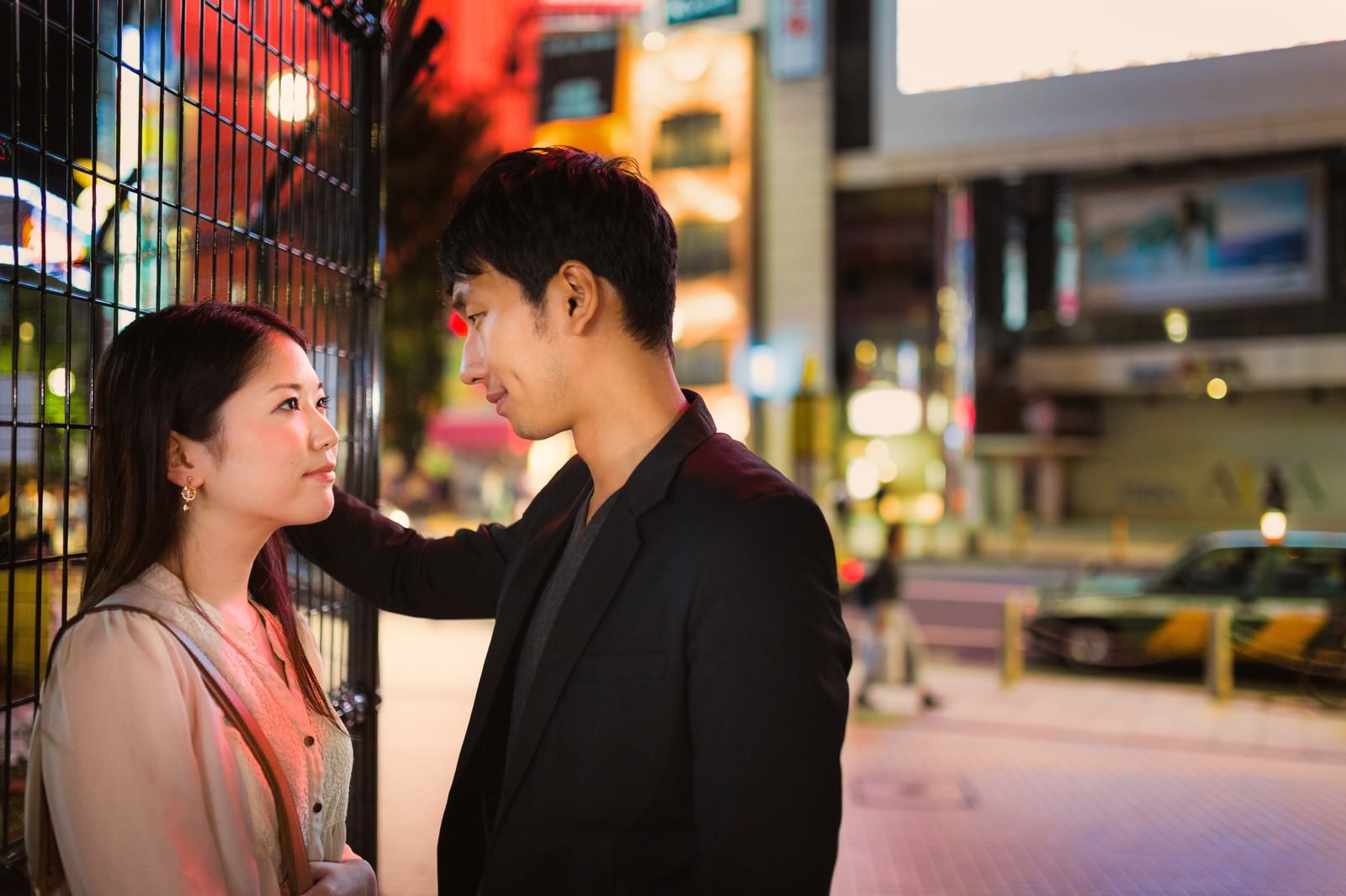 夜の繁華街で向かい合い肩に手を置く男女［モデル：大川竜弥 シマヅ］