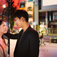 夜の繁華街で向かい合い肩に手を置く男女の写真