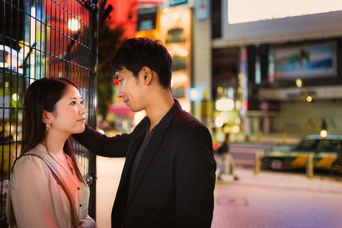 夜の繁華街で向かい合い肩に手を置く男女