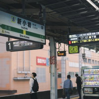 総武線の新小岩駅ホームに停車するオレンジ色の電車の写真