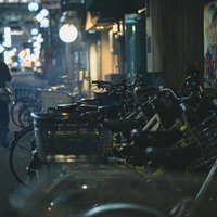 夜の飲み屋街の路地裏に並ぶ駐輪された自転車たちの写真
