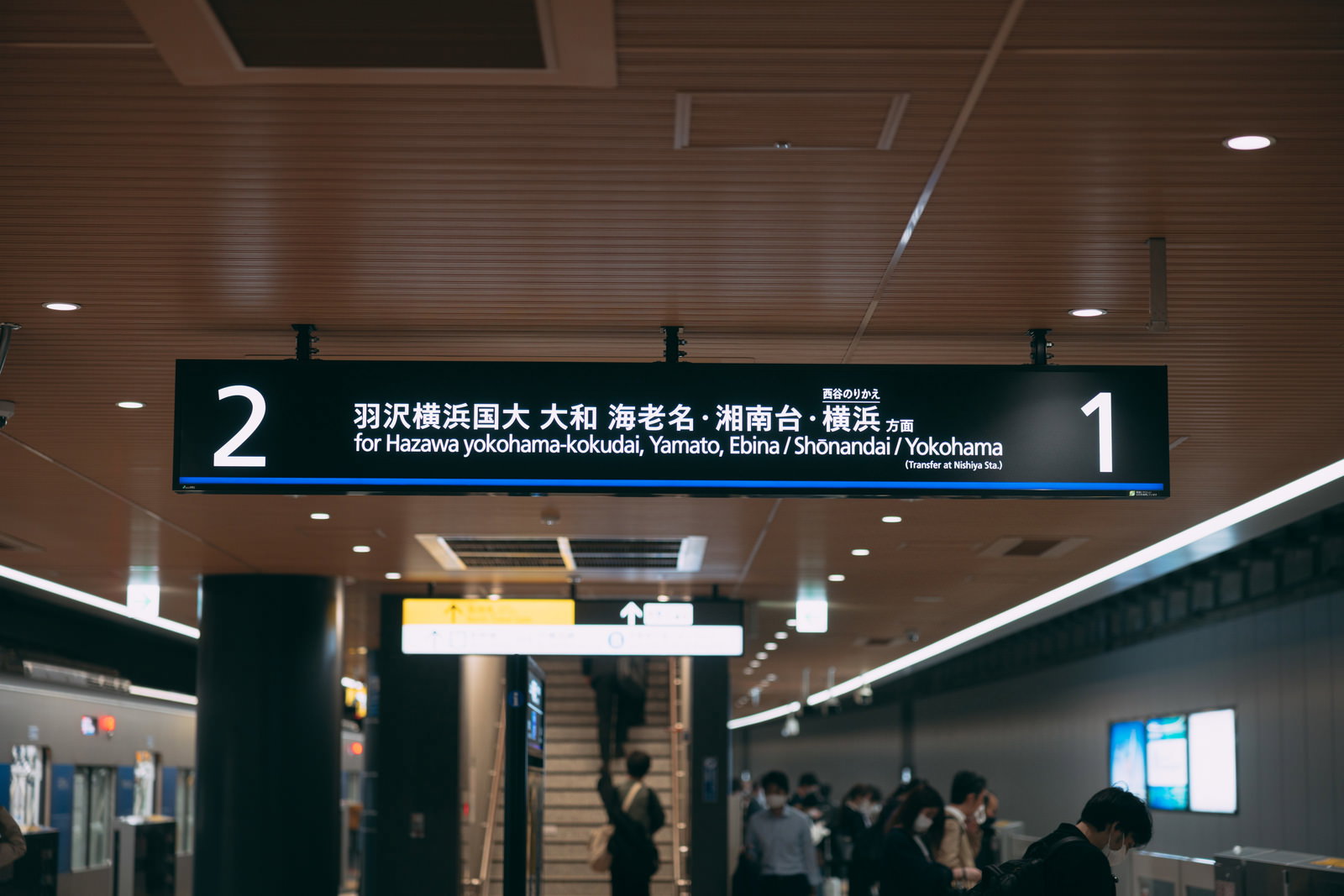 駅の天井に設置された黒い案内標識に新横浜線のホーム番号と行き先が表示されている
