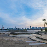 潮風公園の噴水広場から見る夕暮れのビル群とクレーンの写真