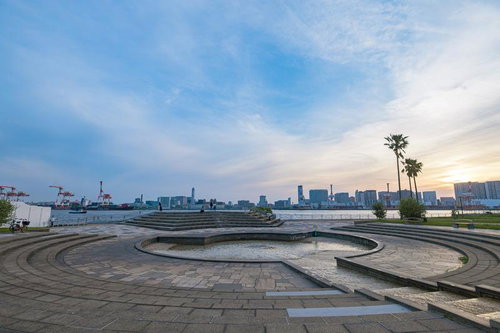 潮風公園の噴水広場から見る夕暮れのビル群とクレーン