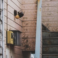 しばらく人が住んでいない廃れたアパートの階段と黄色い公衆電話の写真