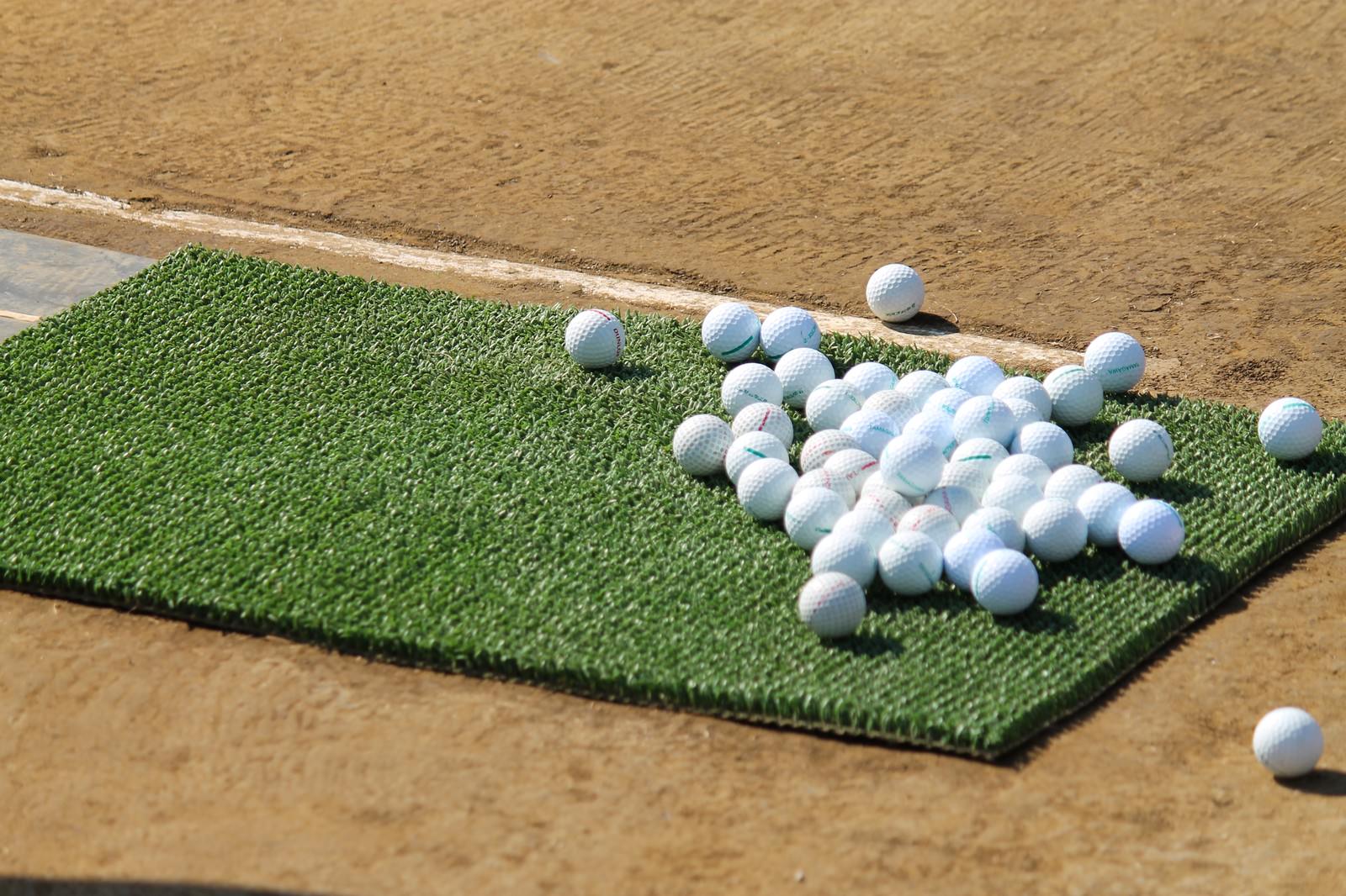 打ちっぱなし練習場の人工芝に並べられた複数のゴルフボール