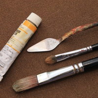 油絵の絵の具とパレット、筆が並ぶ画材道具の写真