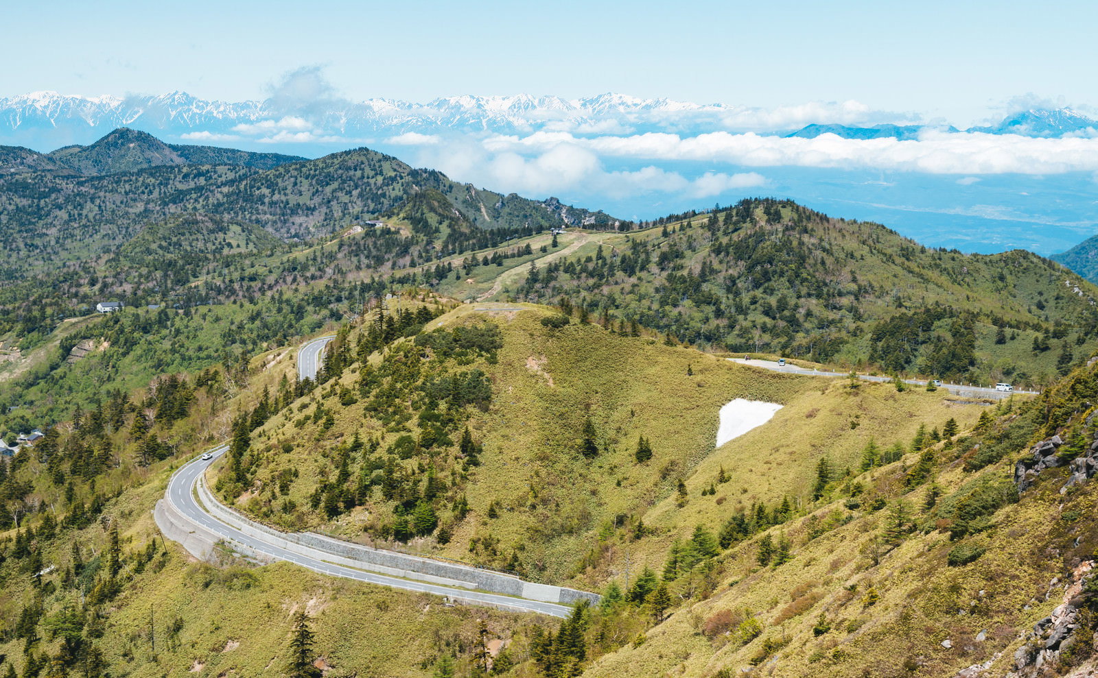 白根山から見下ろした緑の山々とカーブした山道の景観
