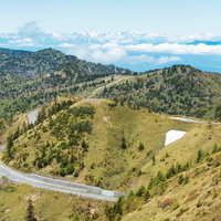 遠くにアルプス山脈が見える白根山からの景観とワインディングロードの写真