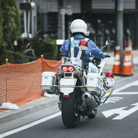 工事現場付近の道路を走行中の白バイによる交通パトロールの写真